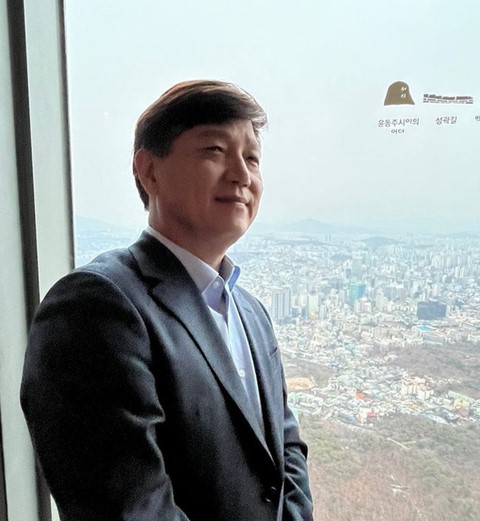 A friendly woman with long dark hair, smiling, dressed in a white blouse and headset.